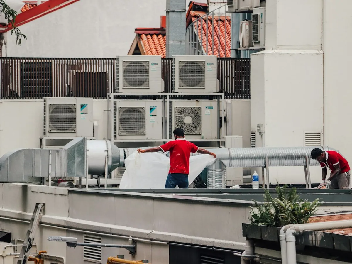 Technicians working on rooftop air conditioning plant