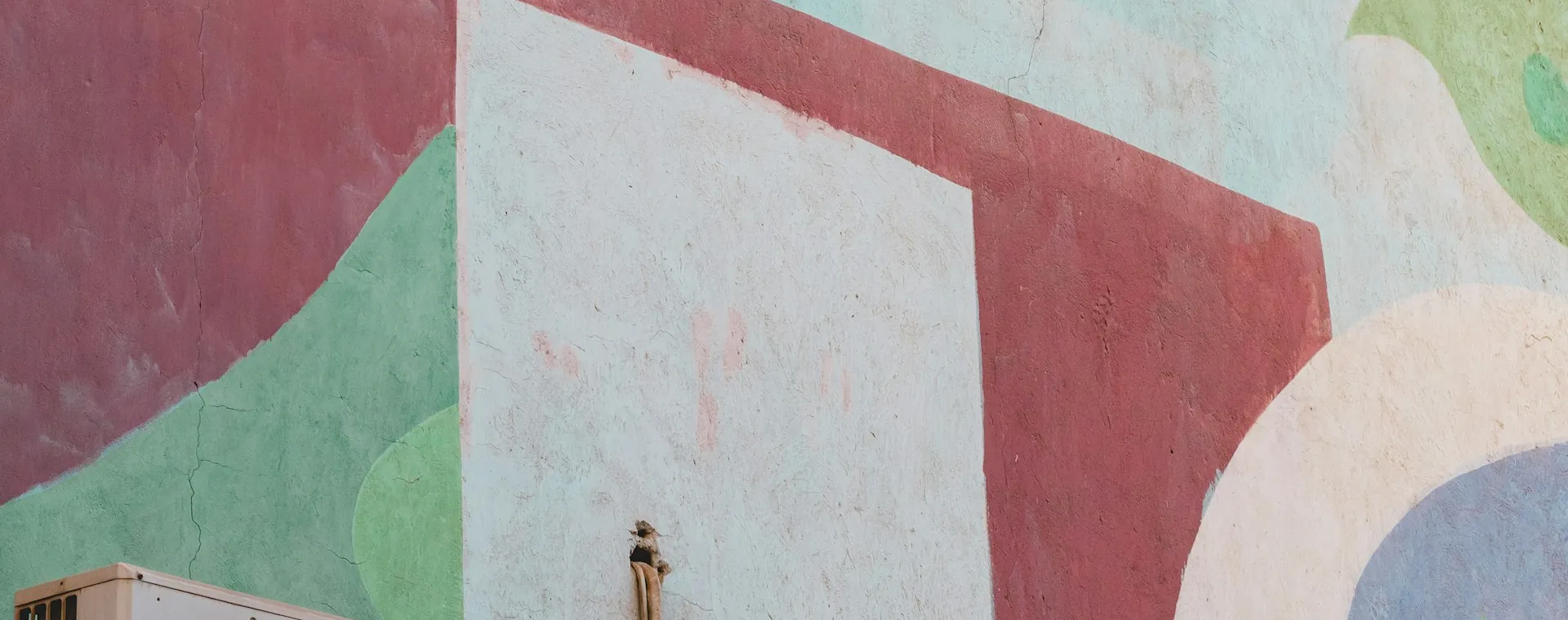 Outdoor AC unit below a painted mural wall