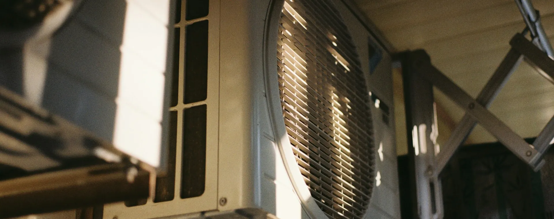 Outdoor AC unit mounted under a roof in evening light