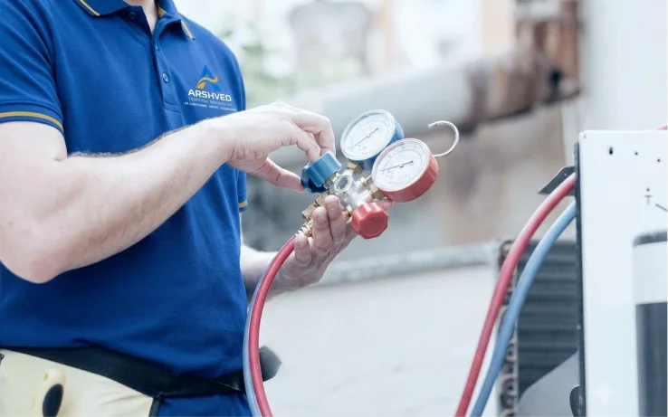 Technician checking refrigerant pressure gauges at an outdoor AC unit