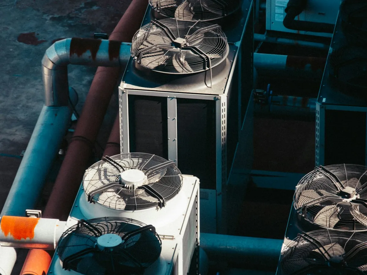 Commercial AC condenser fans and refrigerant pipes on a rooftop